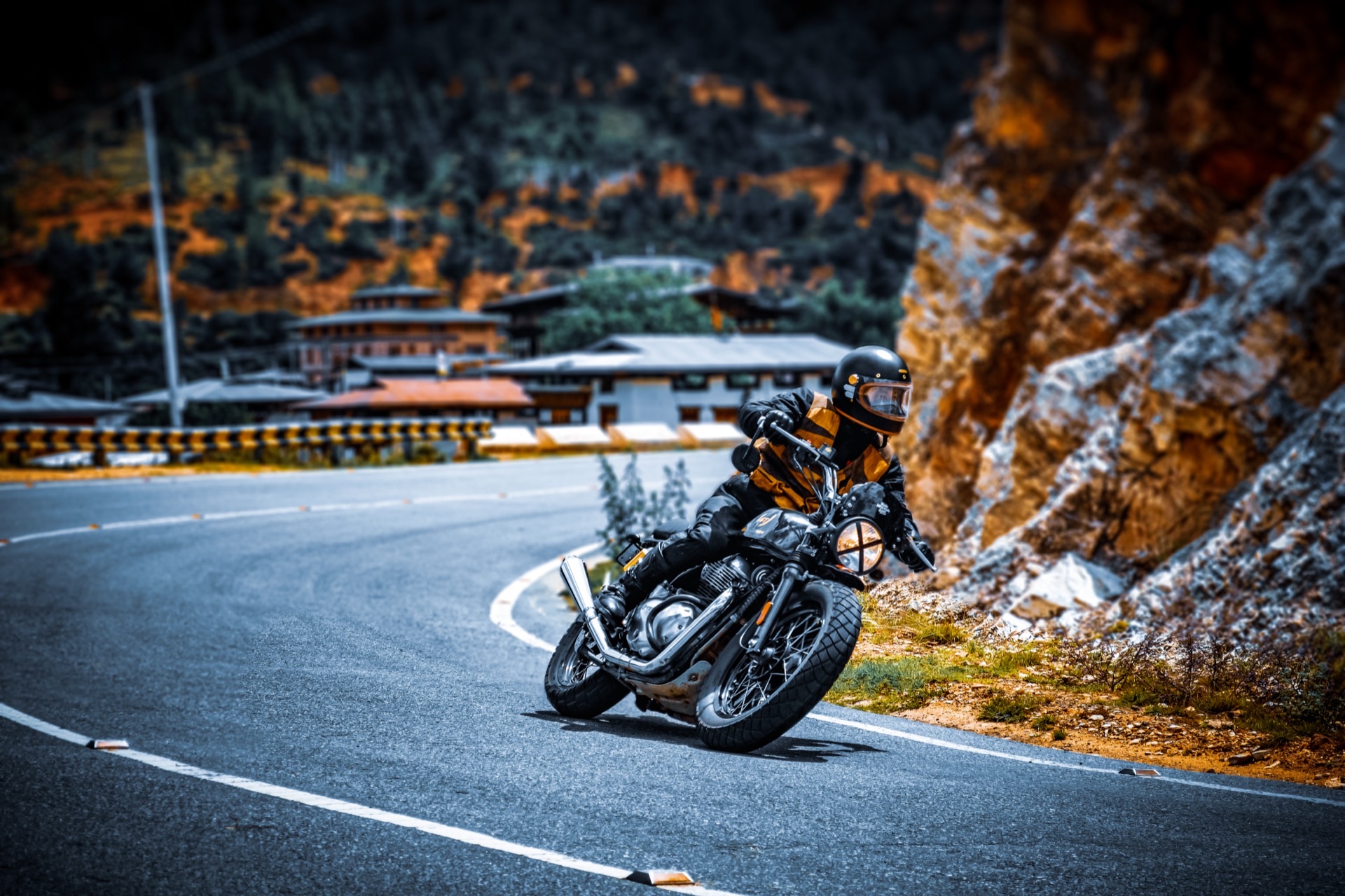 A motorcyclist leaning through a bend on a Bhutanese mountain road