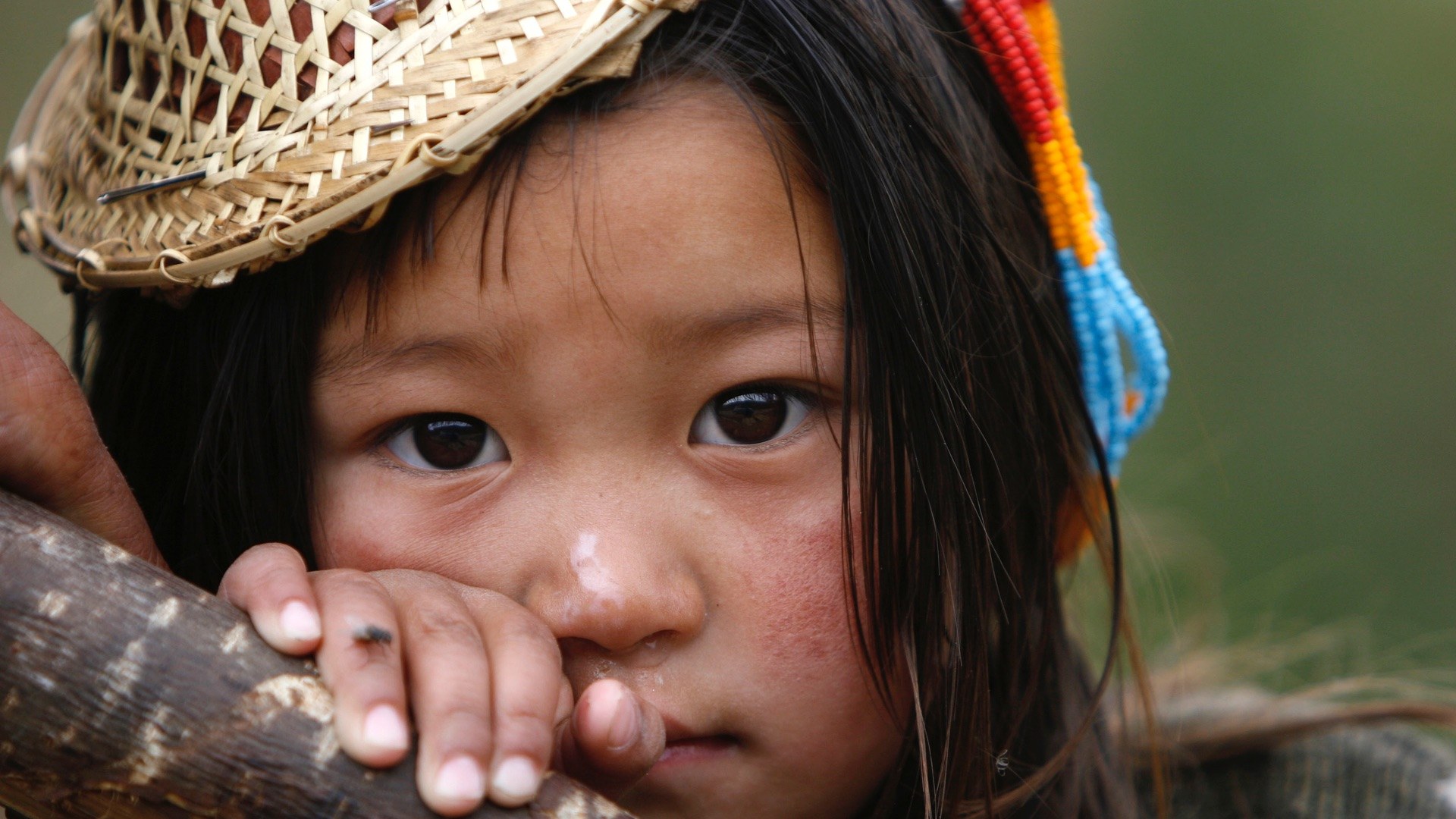 A Bhutanese child in a woven bamboo hat