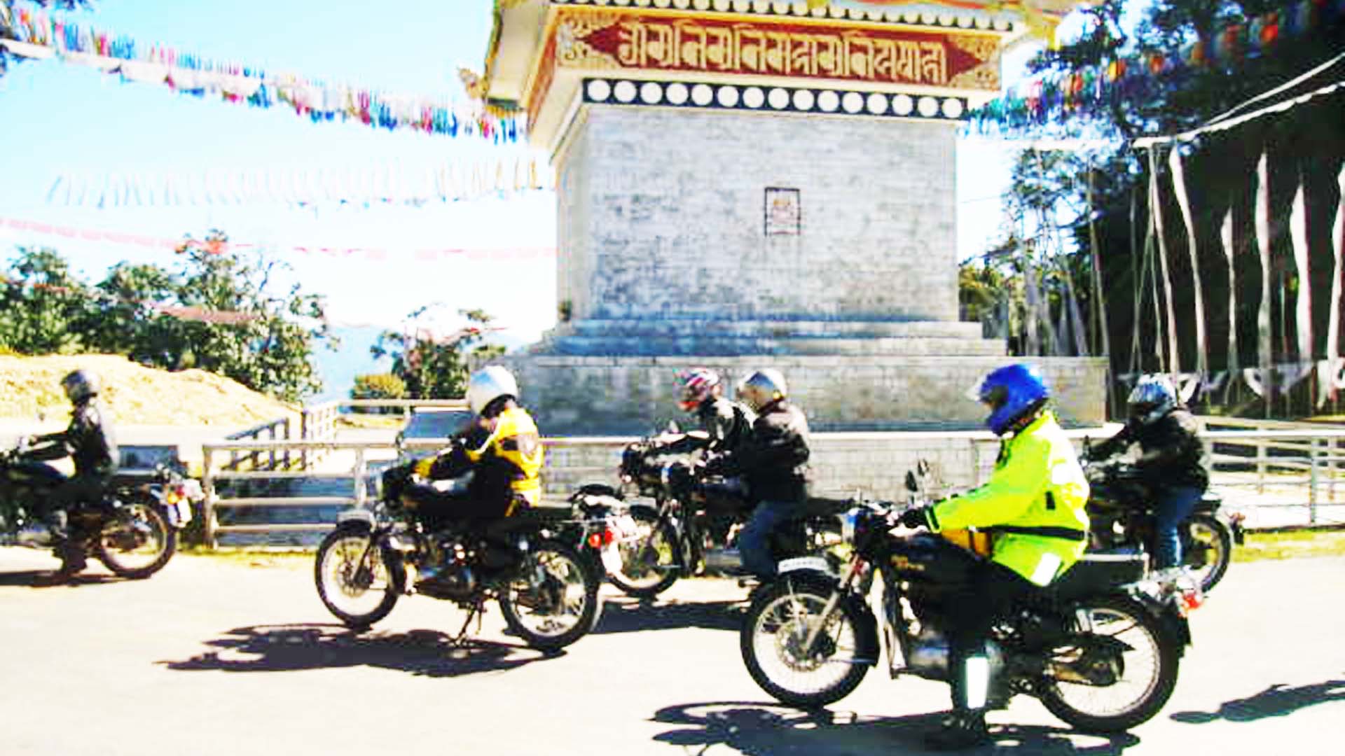 Motorcyclists drawn up at a chorten on a Bhutanese road
