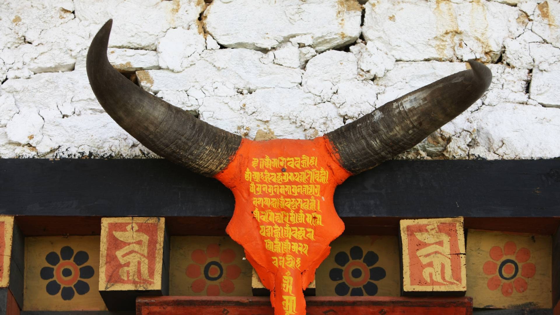 Painted horns and mantra board above a temple doorway